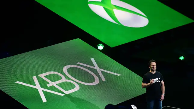 Microsoft Gaming CEO Phil Spencer stands in front of giant Xbox logos.